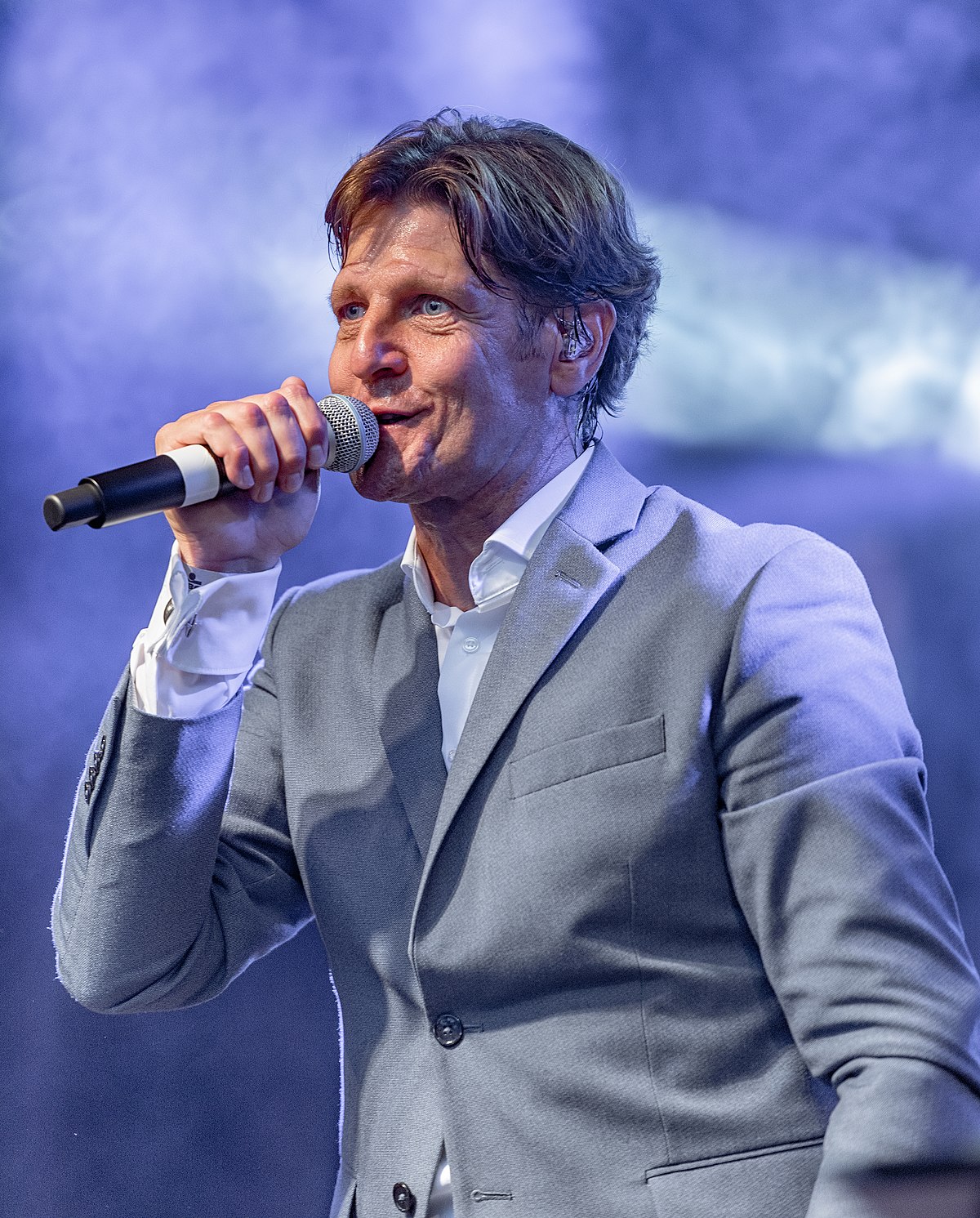 Gunther Neefs zingt live op het podium met warme stem en stijlvolle performance tijdens een sfeervol evenement