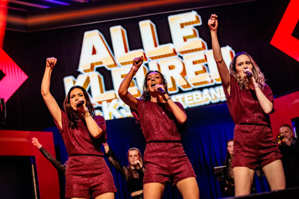Alle Kleuren tribute-act live op het podium in kleurrijke K3-kostuums, zingend en dansend met een enthousiast publiek