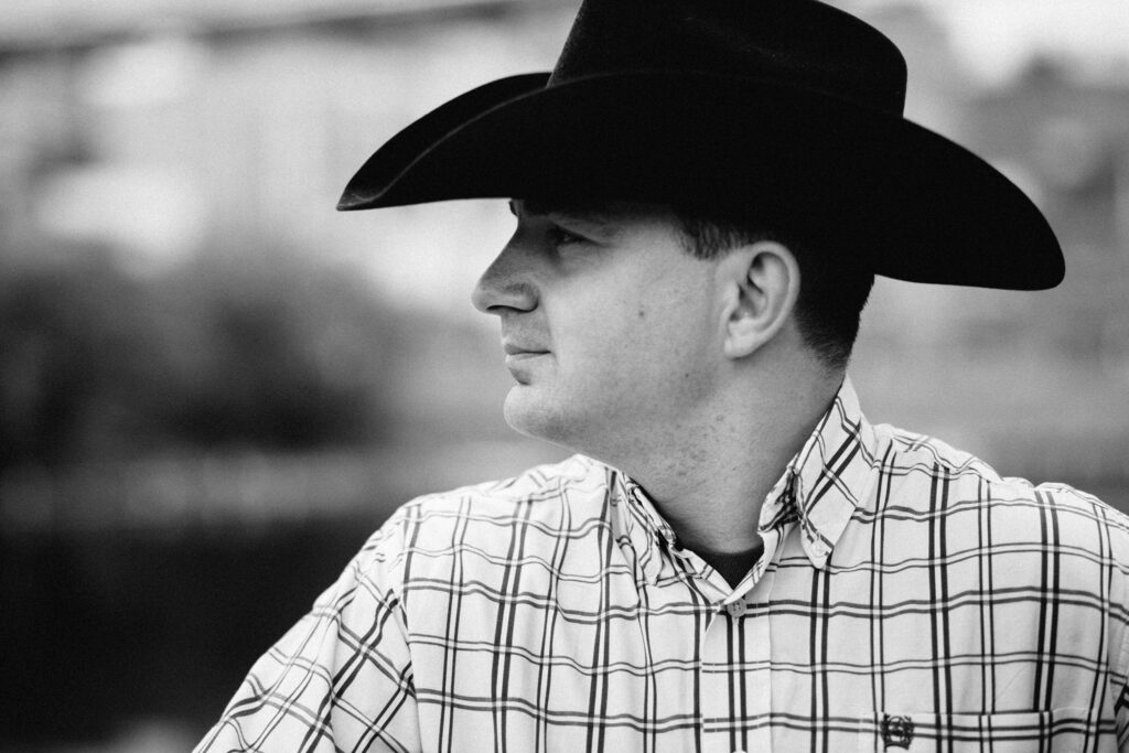 Robby Longo live op het podium met cowboyhoed en gitaar, zingend met diepe stem tijdens een sfeervol country-optreden