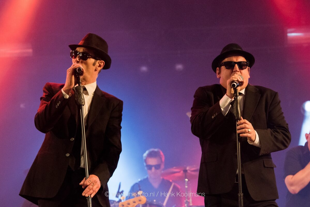 Brothers of Blues tribute band live in actie met zwarte pakken, zonnebrillen en swingende muziek op het podium