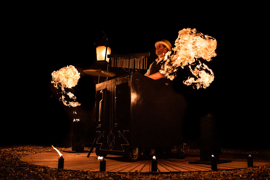Kanza Mees speelt live muziek terwijl vlammen de lucht verlichten bij Muzikaal Vuur onthaalact