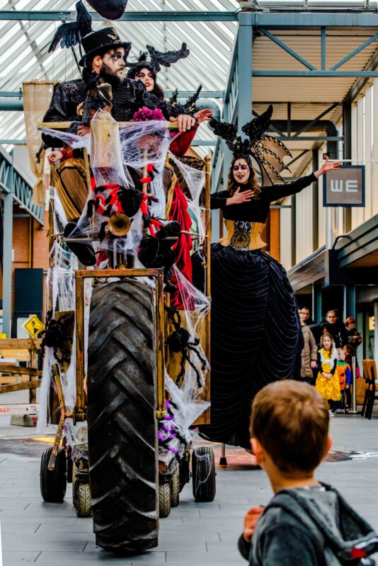 Gigantische rijdende spinnenwagen omringd door webben, rook en Halloween-performers