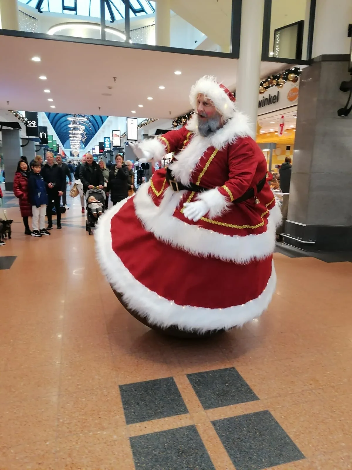 Wiebelende kerstman met twee begeleiders tijdens kerstanimatie op kerstmarkt