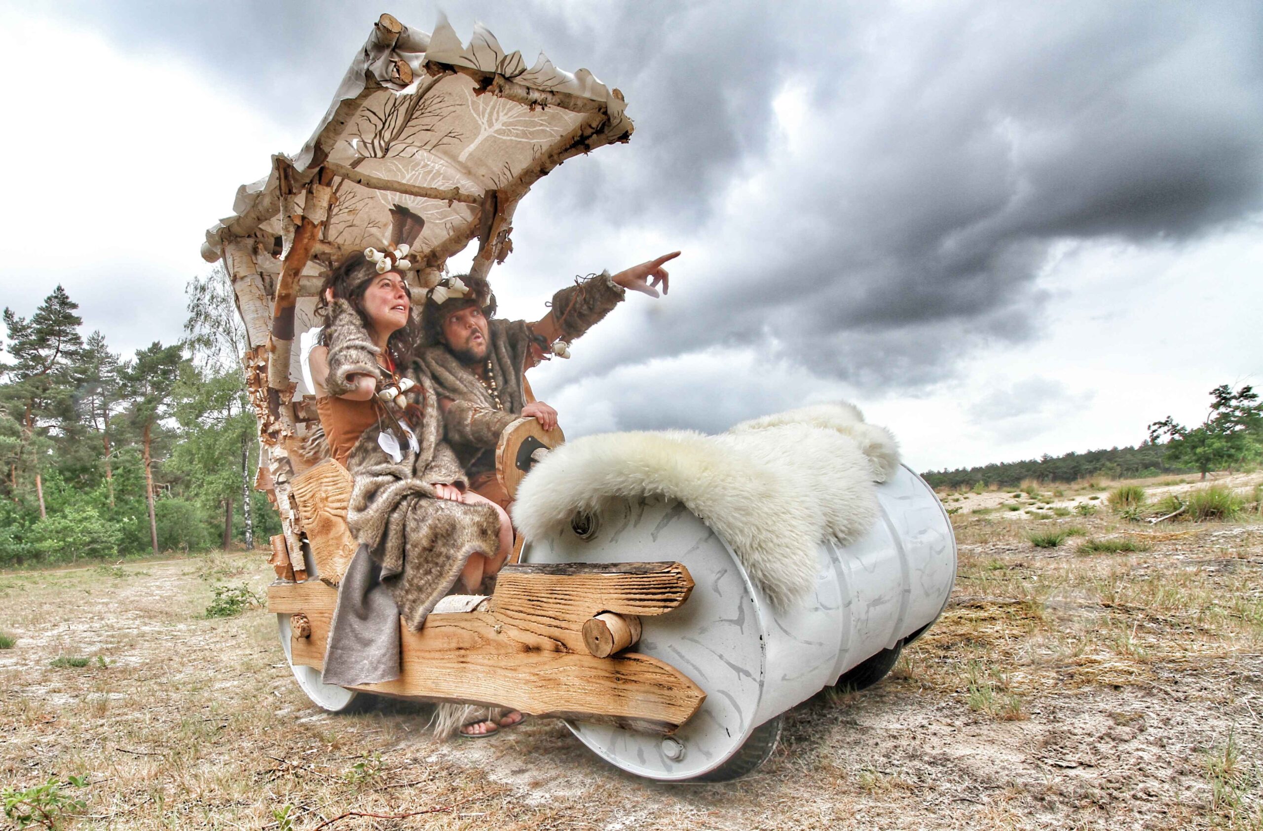 Mobiele straattheateract met holbewoners in prehistorisch kostuum en Flintstone-kar op festival – Dream Animations artiestenbureau