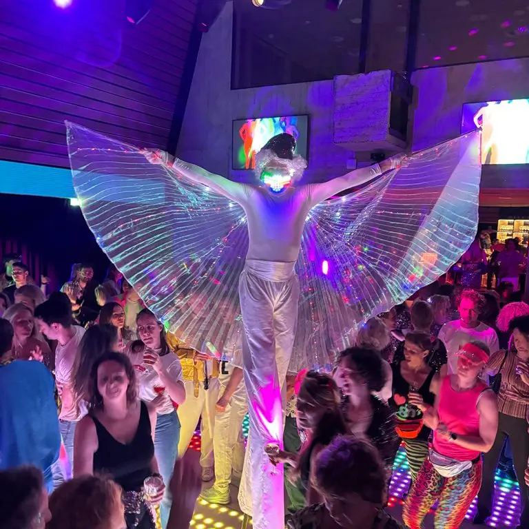 Twee kleurrijk verlichte LED Disco Steltenlopers met oplichtende maskers en vleugels, beschikbaar om te boeken bij Dream Animations voor je event.
