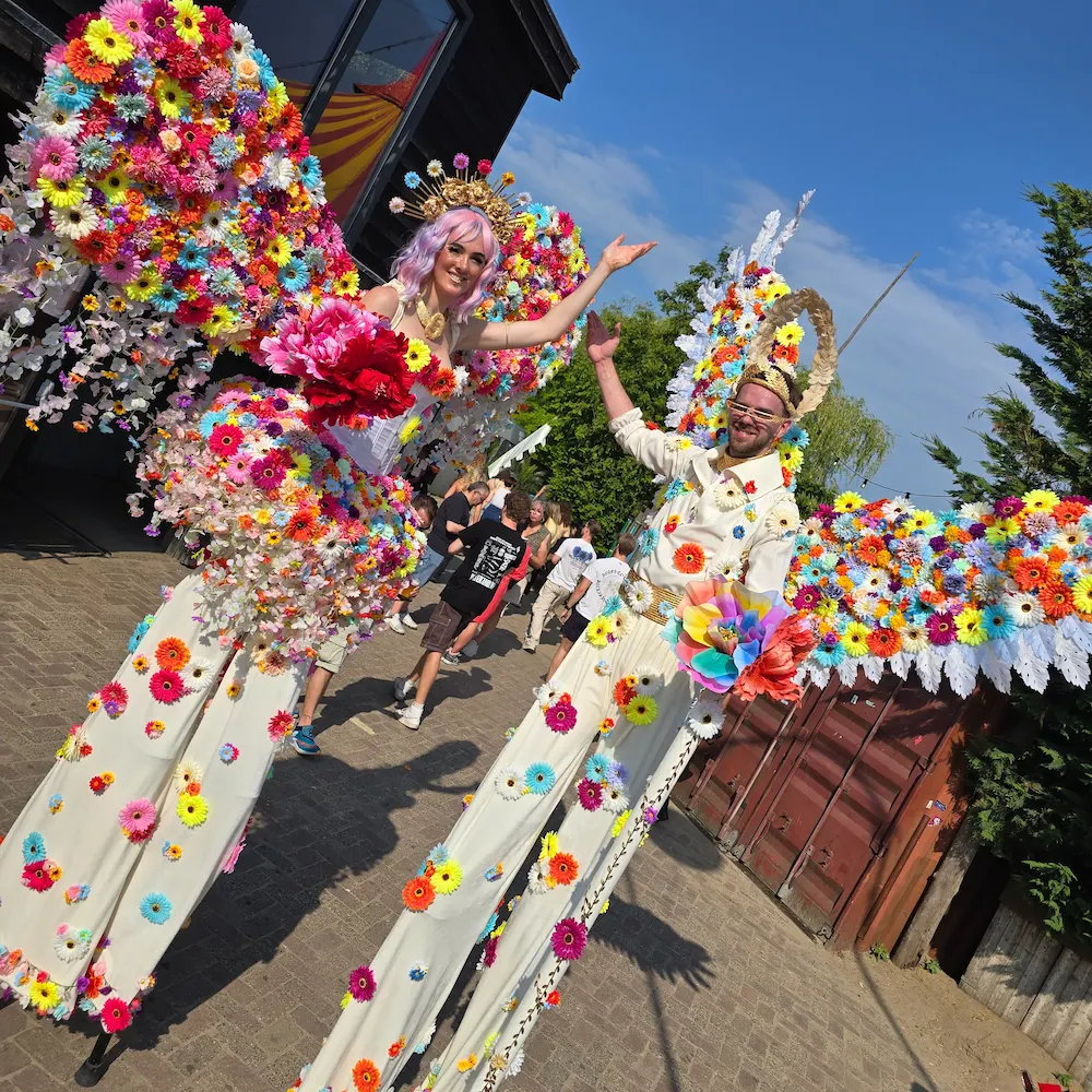 Bloemen steltenlopers in kleurrijke kostuums tijdens straatanimatie op festival of evenement